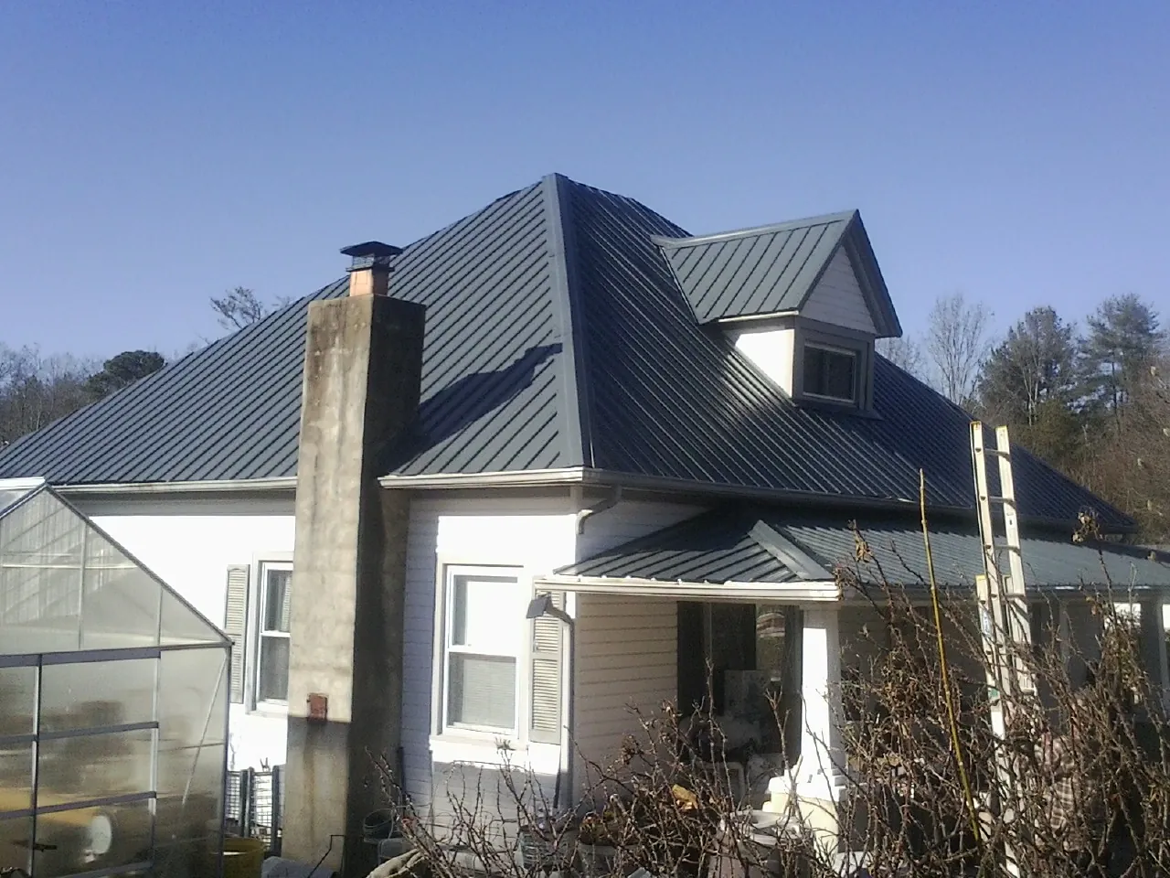 Dark blue standing seam metal roof on a white farmhouse with dormer — Slate & Tile Roof Repair by Roofing Brothers in Tabor