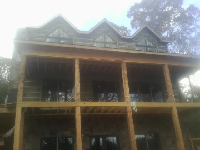 Dormers and porch framing on a large log home under construction — Roof Coating work by our crew in Tabor