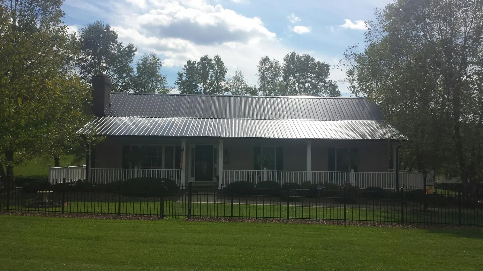 Gray metal roof on a brick ranch with a full width front porch — Gutter Guard Installation work by our crew in Tabor