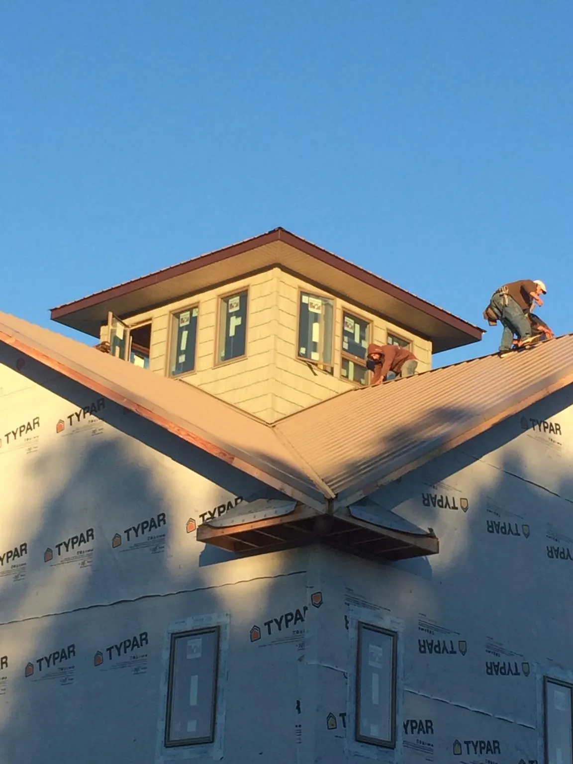 Roofers working around a rooftop cupola on a new metal roof at sunset — Roof Waterproofing in Tabor by Roofing Brothers